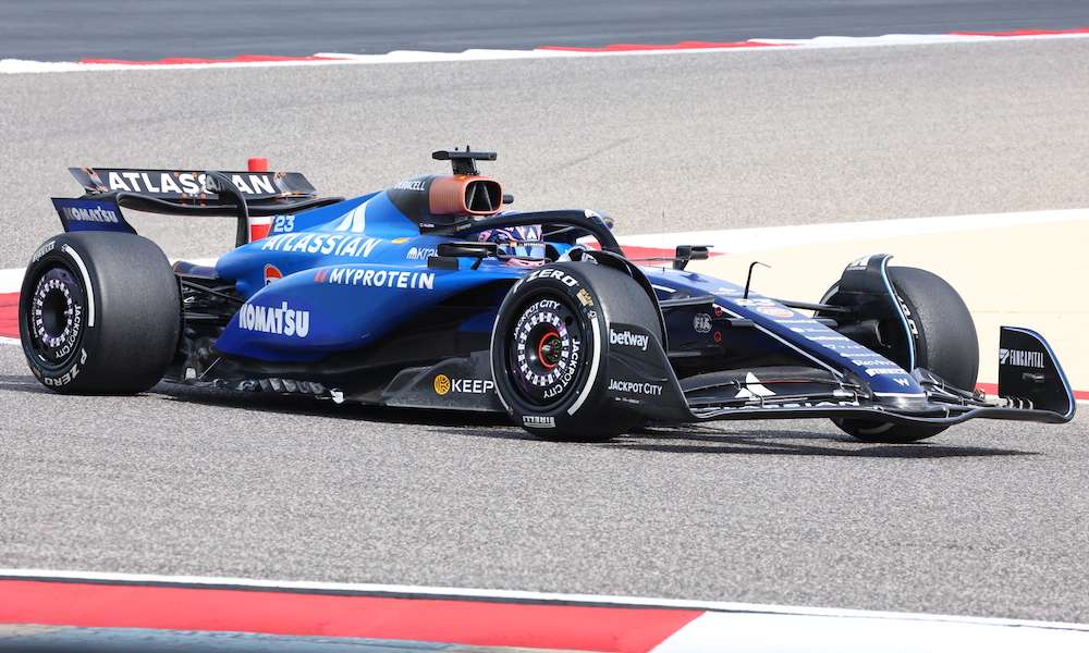 Alex Albon gripping the steering wheel intensely during a high-speed corner with focused expression