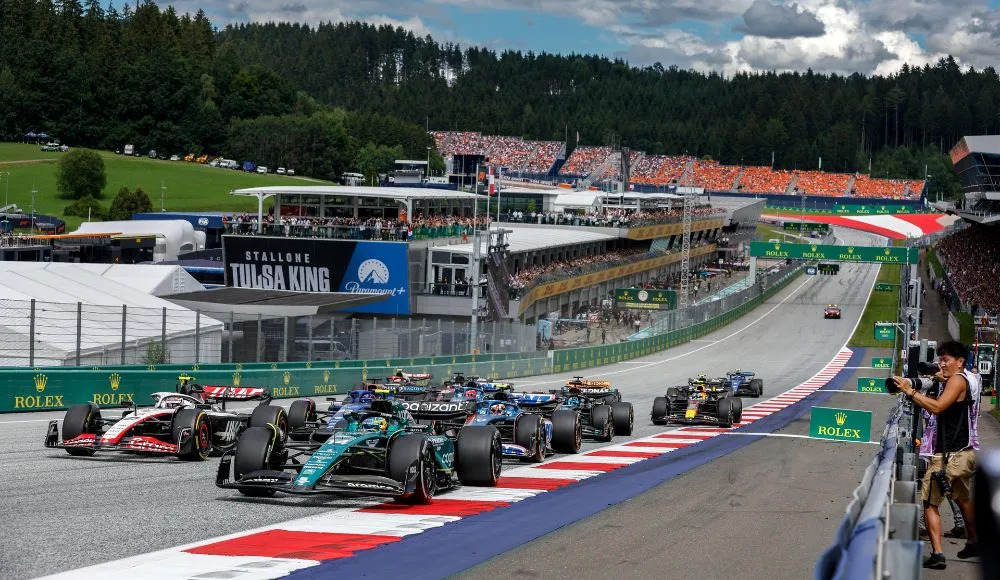 Car braking hard into Turn 1 at the Red Bull Ring with visible brake glow