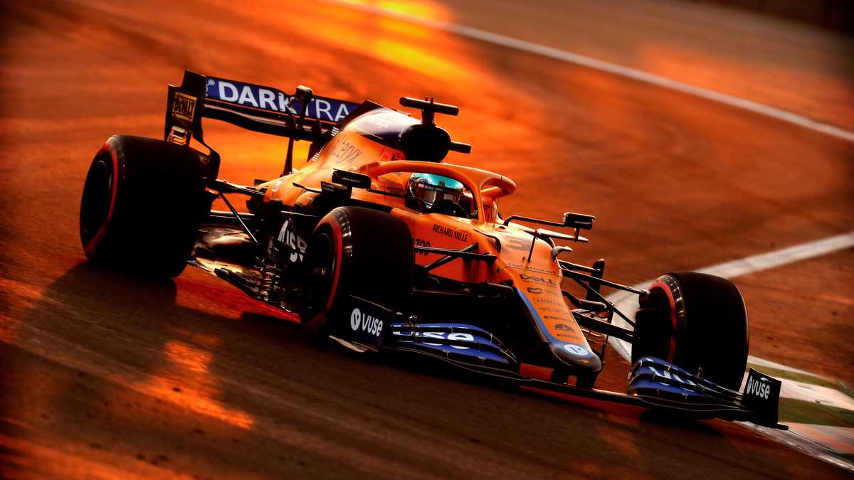 Lando Norris in racing gear at a junior academy event, representing modern driver development