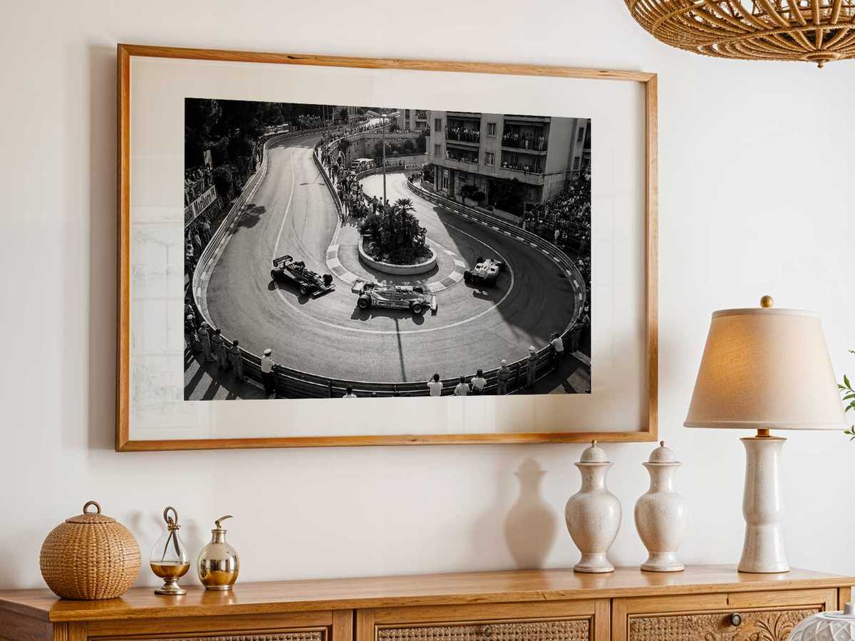 Sunlit building facades casting long shadows across a tight Monte Carlo corner as cars navigate the turn