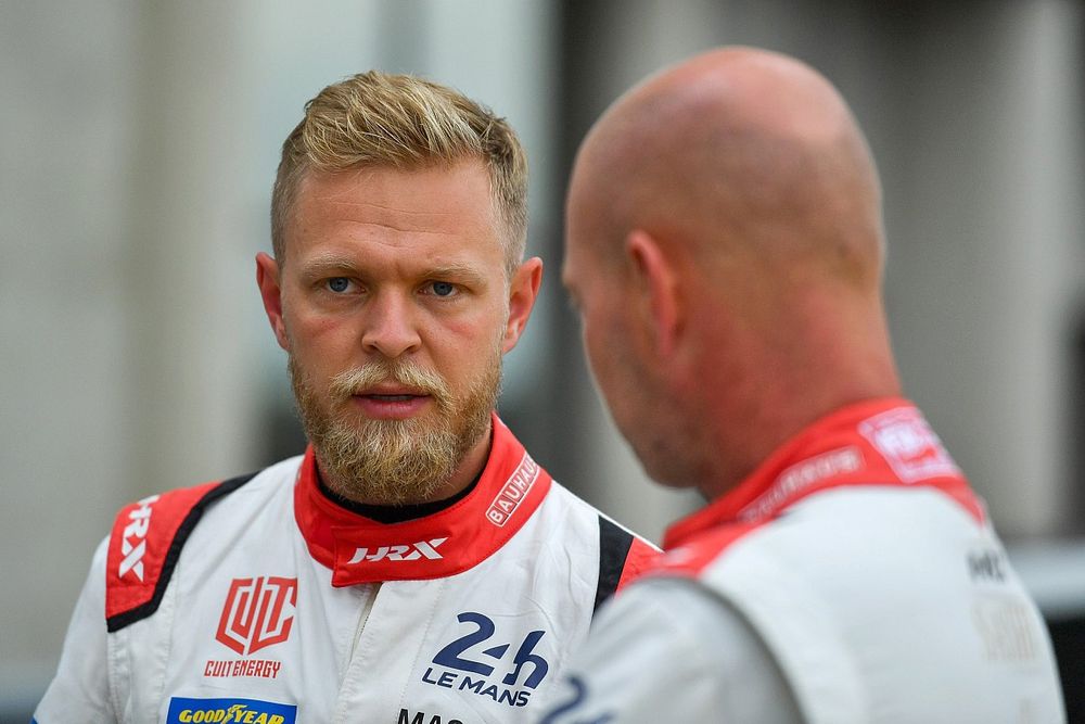 Kevin Magnussen celebrating on the podium after his surprise debut podium finish, holding champagne and smiling at the crowd