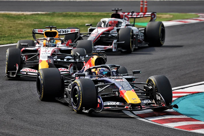 Red Bull Racing car blasting down Monza main straight with motion blur and pit complex in background